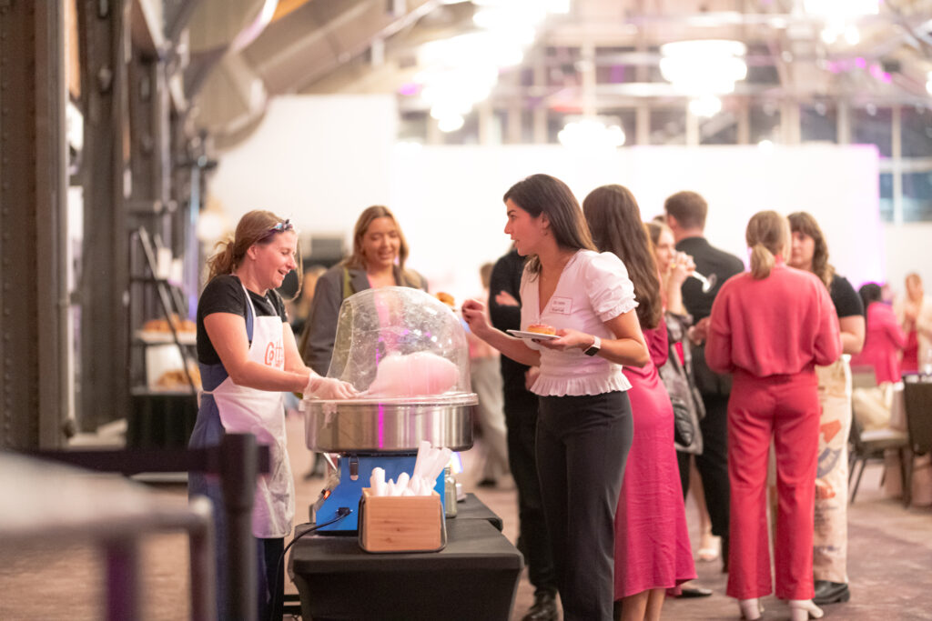Guests at the Women's Leadership Panel enjoying cotton candy from a dessert booth.